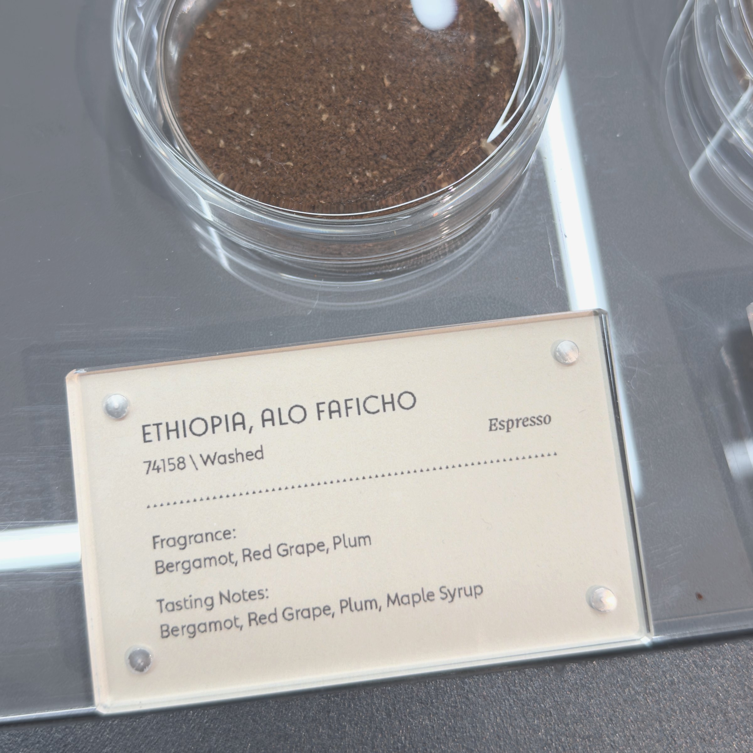 Ground coffee beside a card naming the lot, process and tasting notes