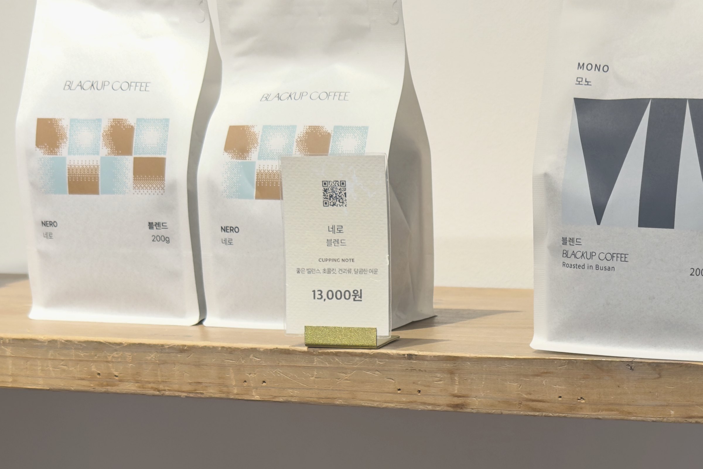 A retail shelf of Blackup Coffee bags in Busan, with a price card reading 13,000 won and a QR code