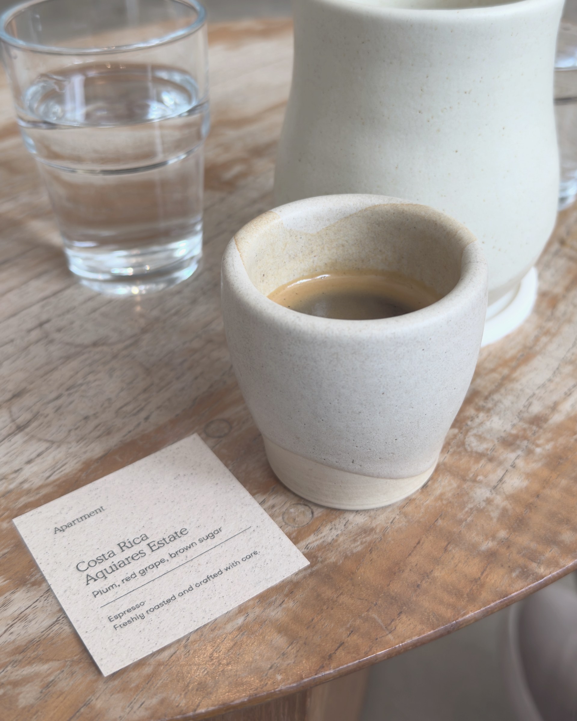 A card beside an espresso reading: Costa Rica, Aquiares Estate, plum, red grape, brown sugar